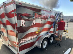 Red-and-white Double D Racing trailer with a person standing beside it at a racing event.