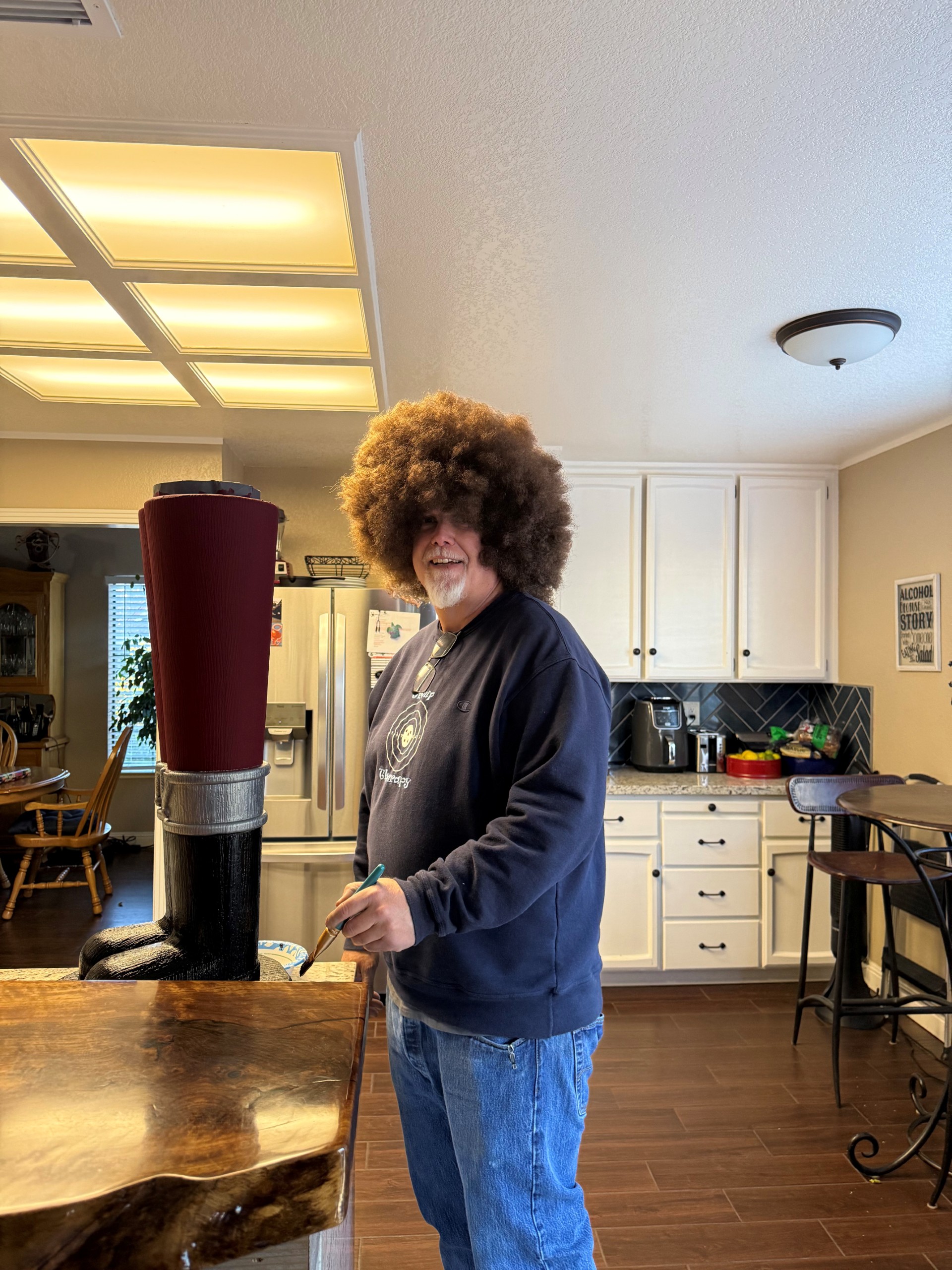 Charles Dandy dressed up as Bob Ross completing an art project